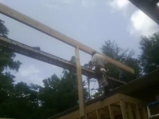 Carpenter setting a ridge beam over a new addition frame — Ice Dam Removal by Roofing Brothers in Lexington Park