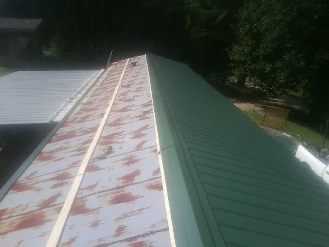 Old rusted panels beside newly installed green metal roofing — Wind Damage Roof Repair by Roofing Brothers in Lexington Park