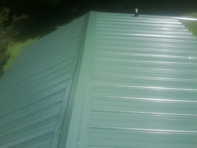 New green metal panels meeting at the ridge of a roof — Flat Roof Repair work by our crew in Lexington Park
