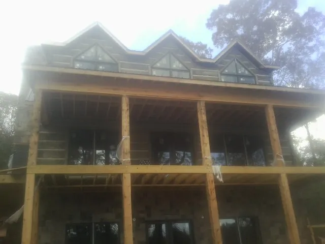 Dormers and porch framing on a large log home under construction — Roof Coating work by our crew in Lexington Park