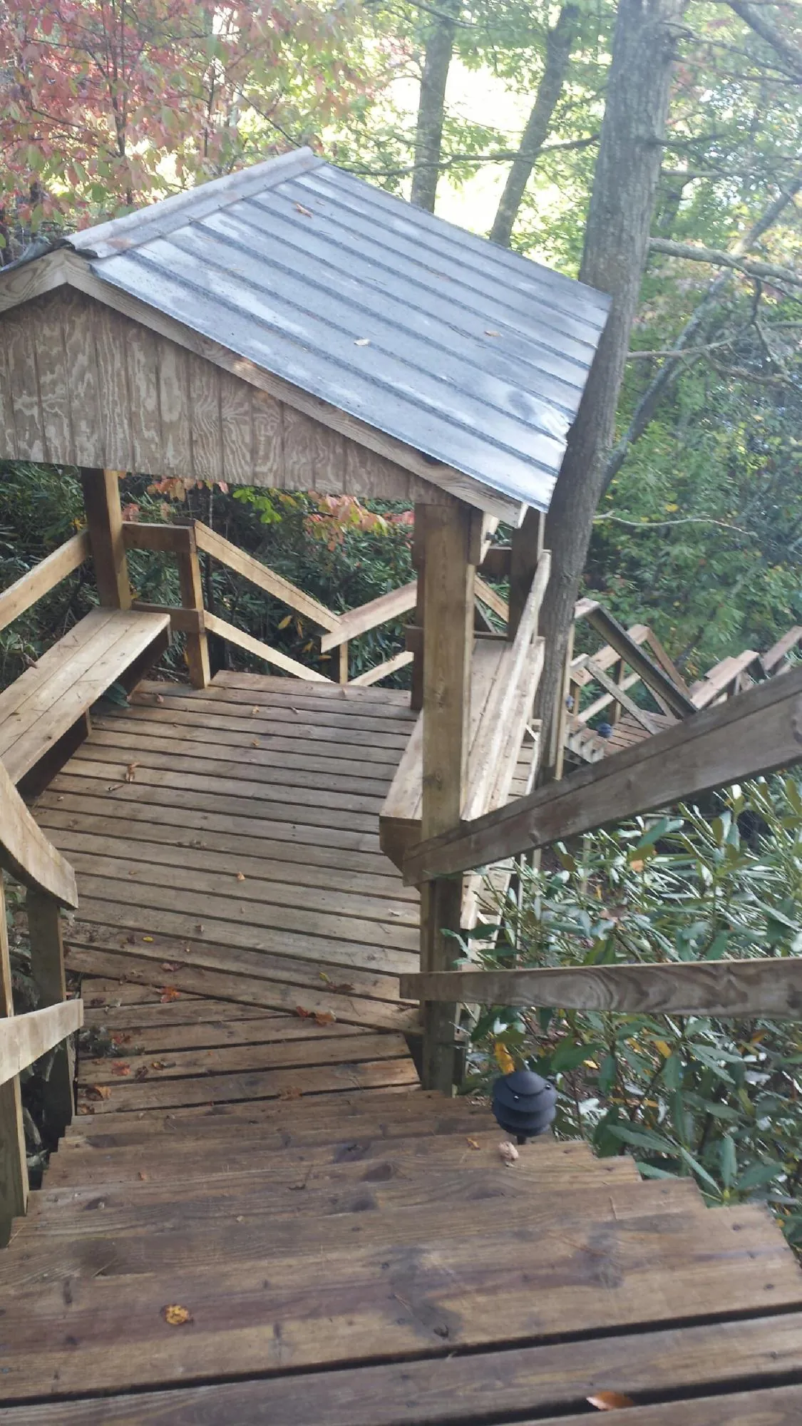 Metal roofed shelter over wooden steps on a wooded walkway — Skylight Repair & Installation work by our crew in Lexington Park