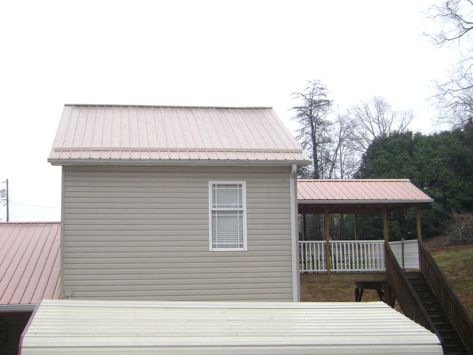Tan metal roofs on a two story addition and attached porch, from a Roof Replacement job in Lexington Park